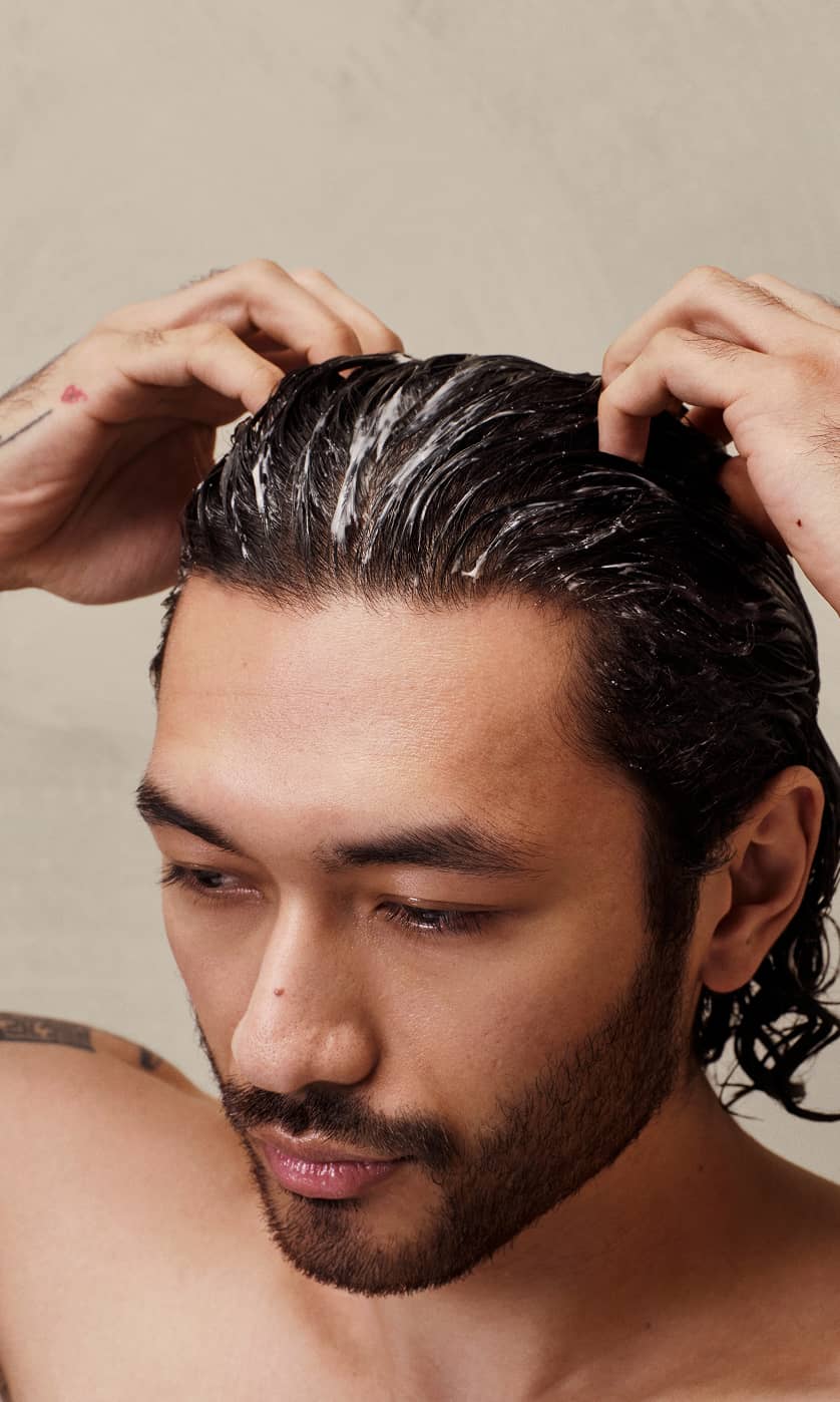 A man massaging his personalized scalp mask into his scalp with the text “Powered by prebiotics, postbiotics, and probiotics”.