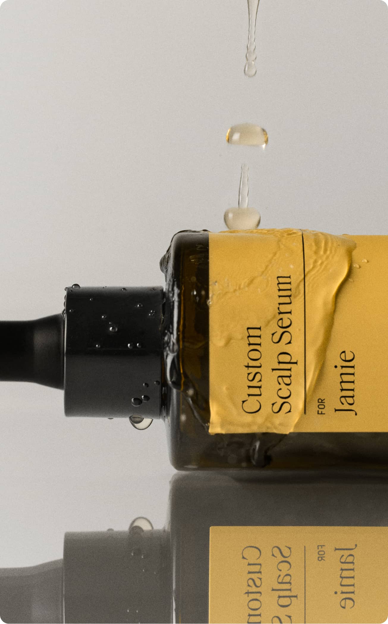 Close-up of a Prose Custom Scalp Serum bottle with serum in use.