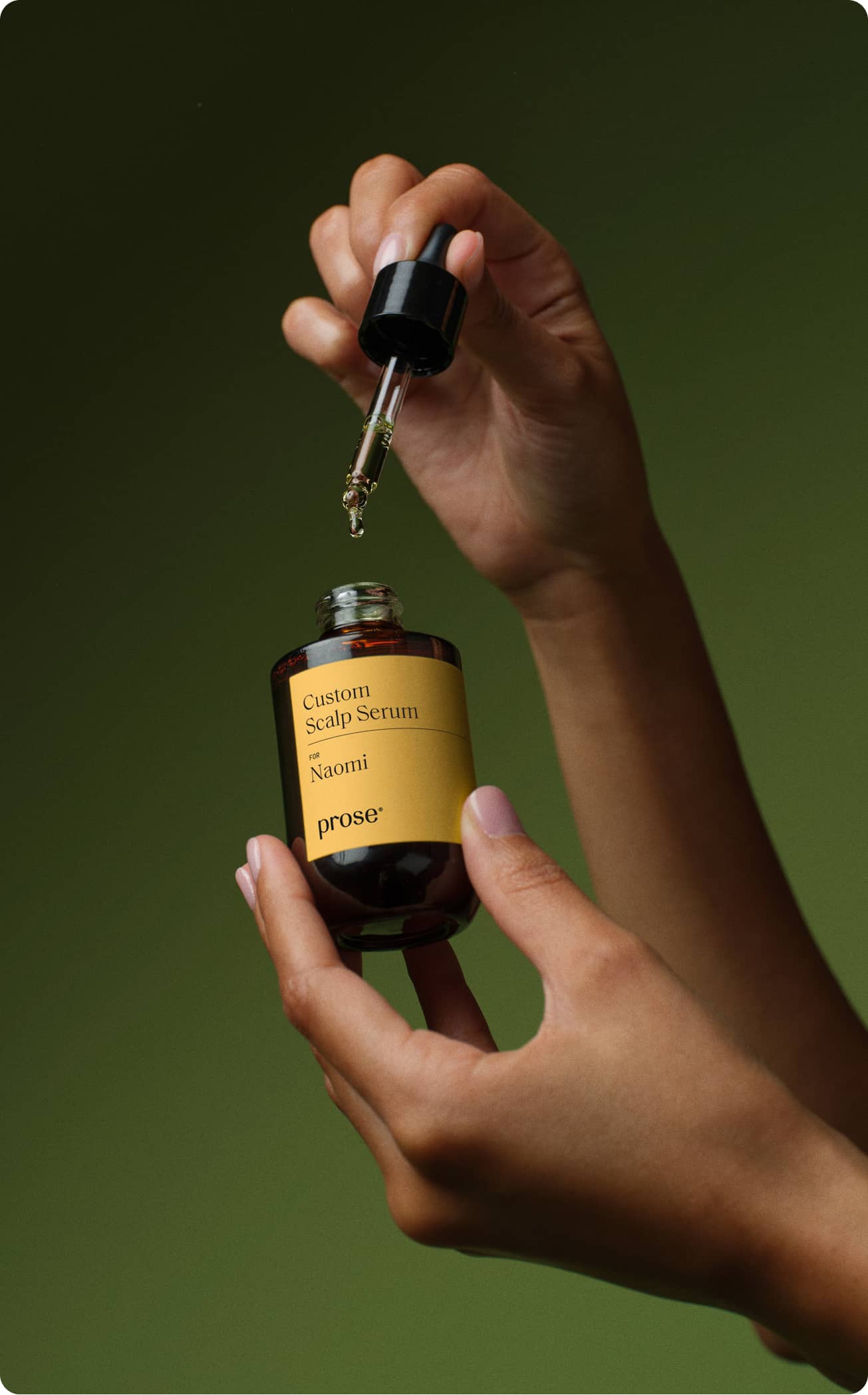Close-up of a hand gripping a bottle of Prose Custom Scalp Serum, featuring a clear and attractive label design.