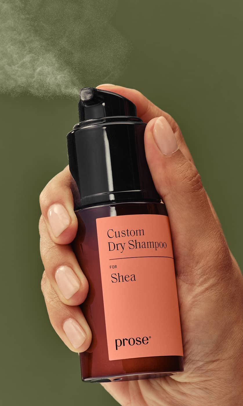 Hand spraying a Prose Custom Dry Shampoo bottle labeled “for Shea”.