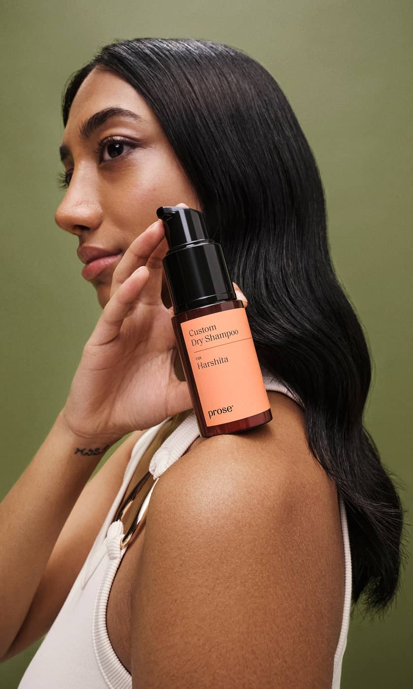 Model holding a Prose Custom Dry Shampoo bottle against her hair.