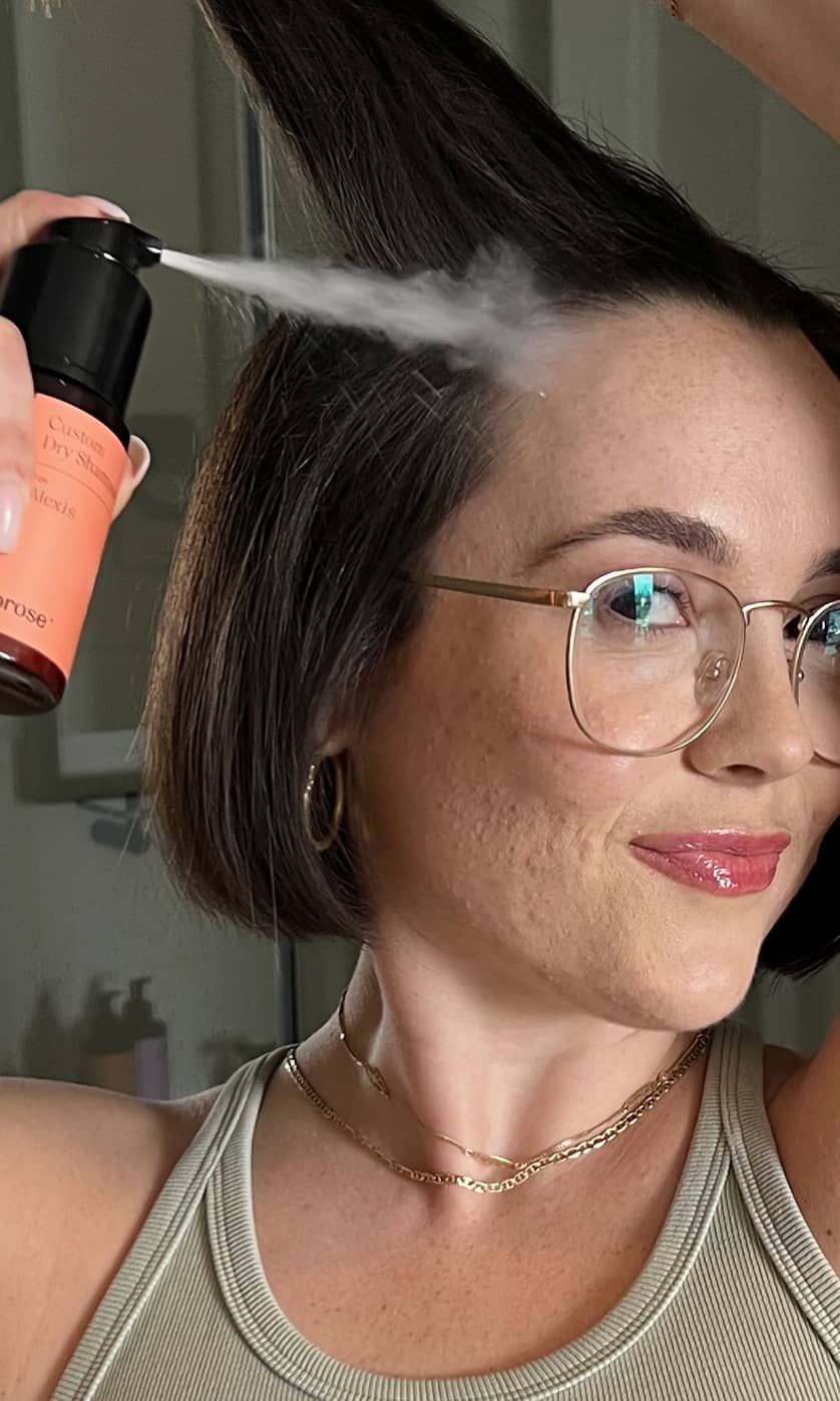 Woman misting Prose Custom Dry Shampoo into her roots.